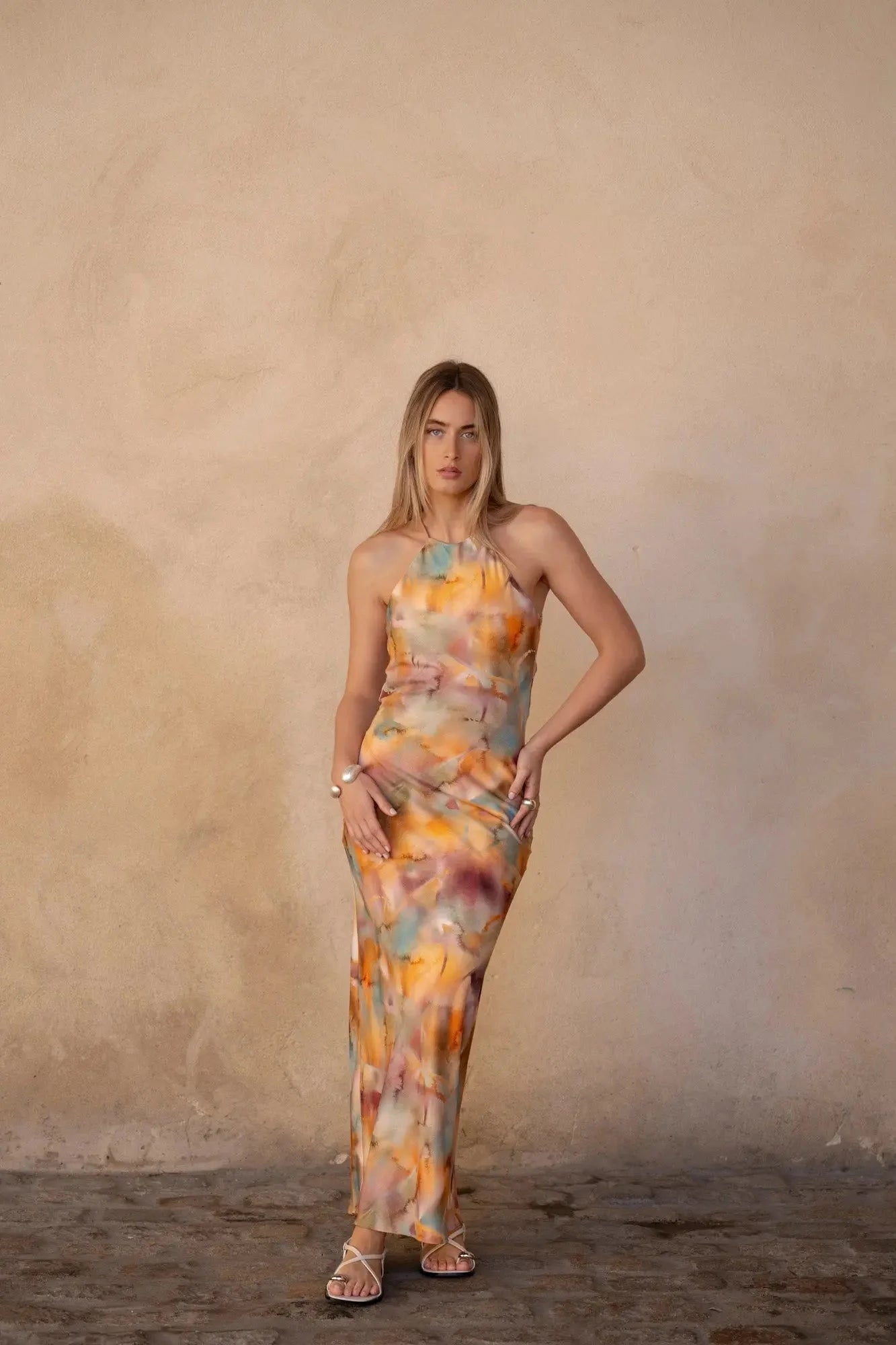 Modèle mettant en avant la robe satin longue dos nu imprimée aquarelle multicolore – Élégance fluide et chic, capturant une allure sophistiquée.