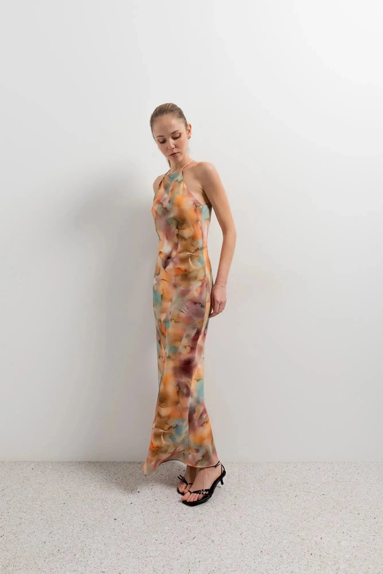 Modèle en pose contemporaine avec la robe satin longue dos nu imprimée aquarelle multicolore – Élégance fluide et chic, affichant un style unique.