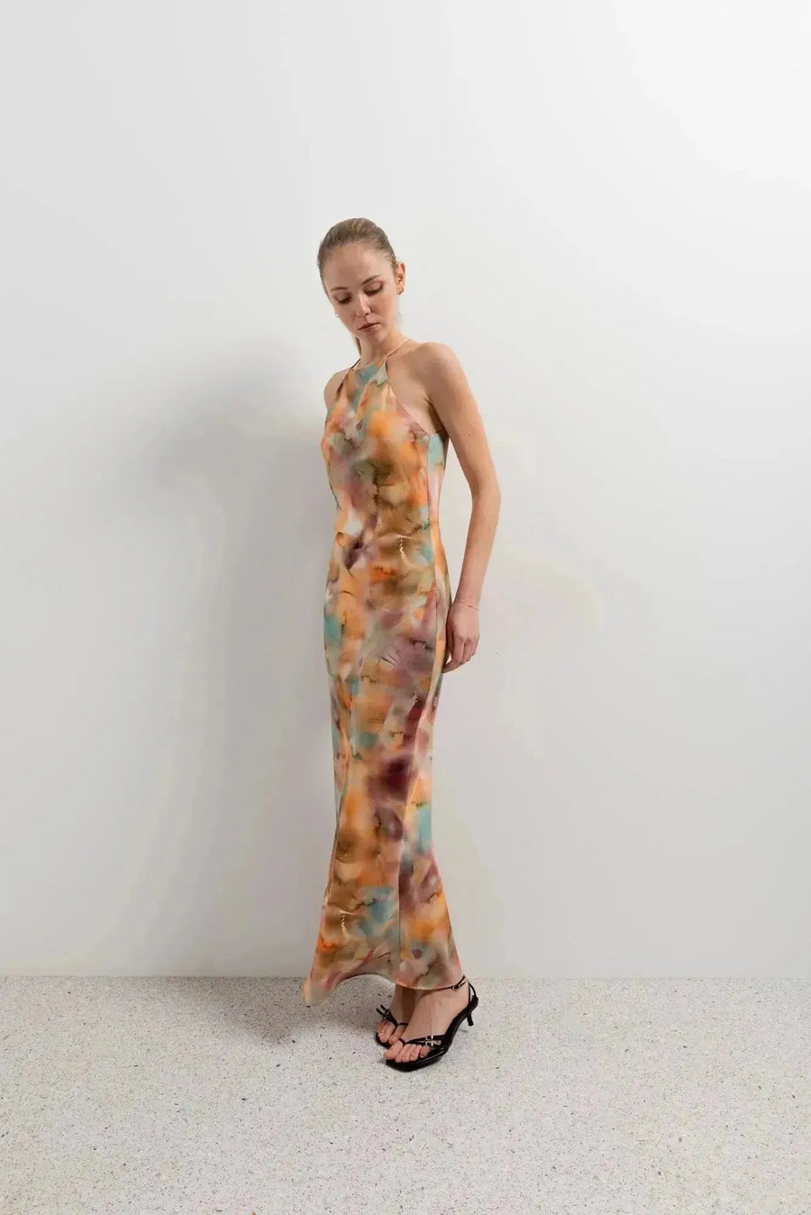 Modèle en pose contemporaine avec la robe satin longue dos nu imprimée aquarelle multicolore – Élégance fluide et chic, affichant un style unique.