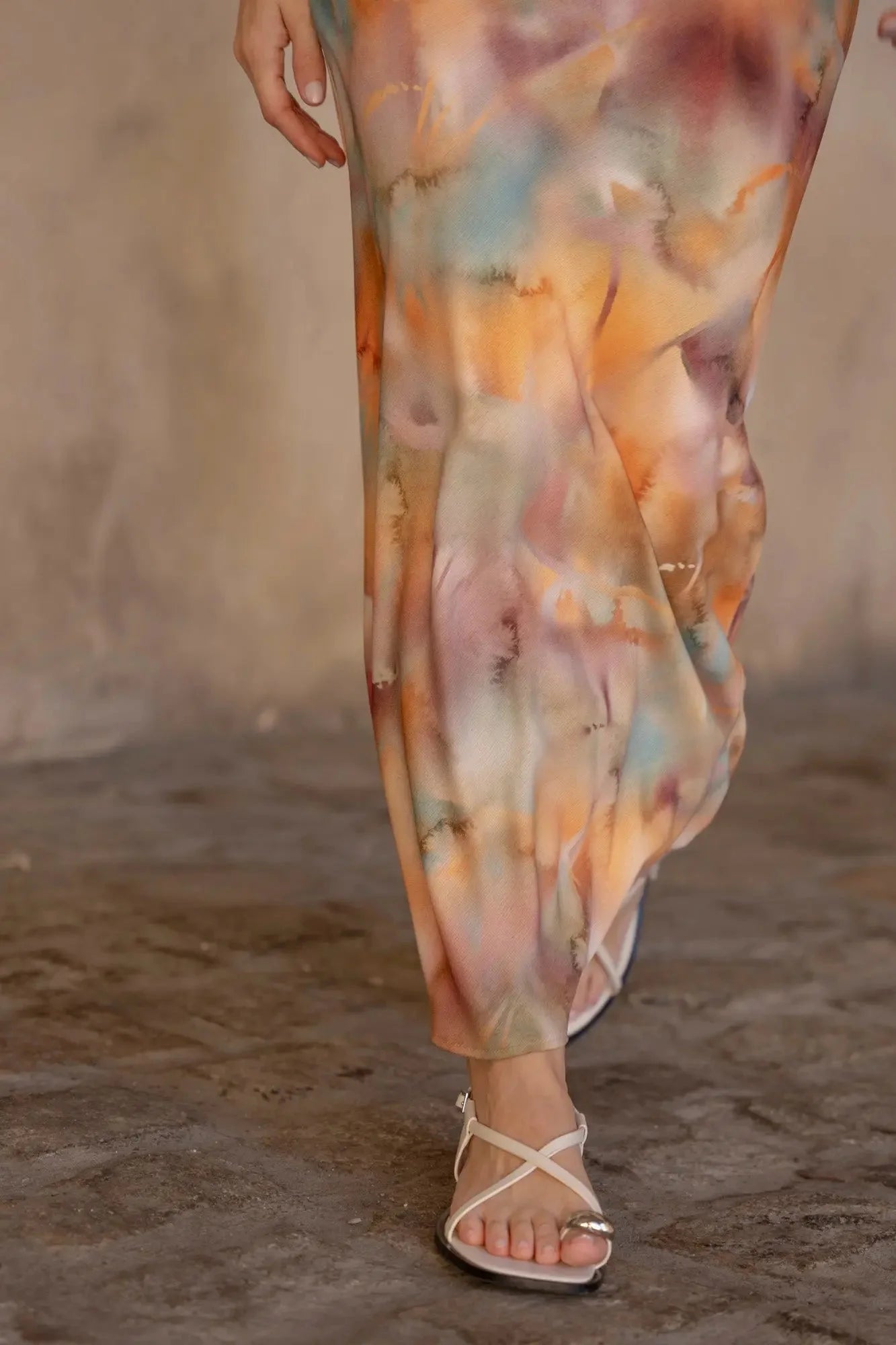 Détails des jambes du modèle portant la robe satin longue dos nu imprimée aquarelle multicolore – Élégance fluide et chic, montrant la fluidité du tissu.