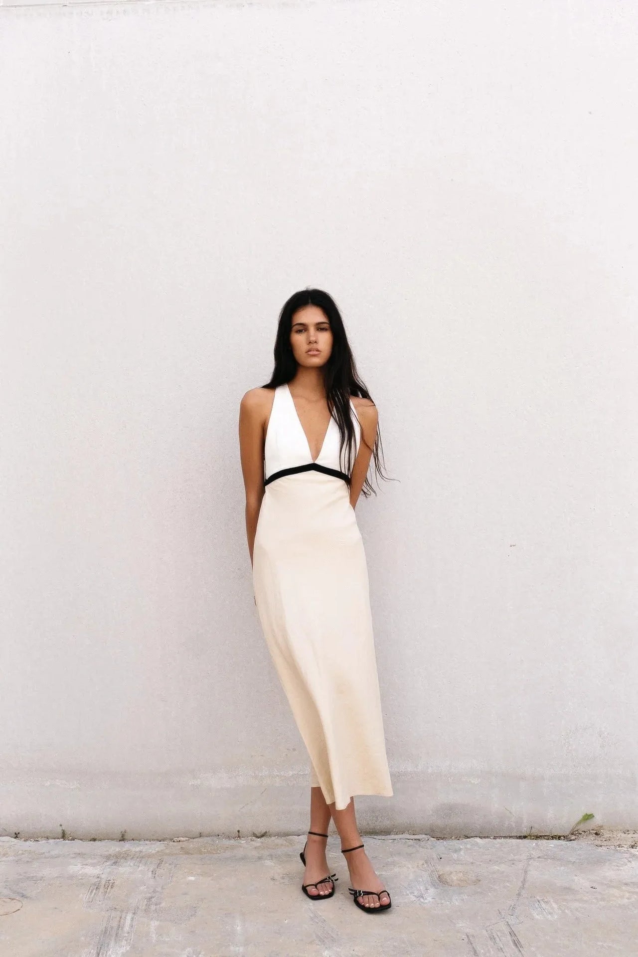 Vue complète d'un modèle en robe longue dos nu écru, mettant en valeur son décolleté plongeant et son élégance pour les occasions estivales.