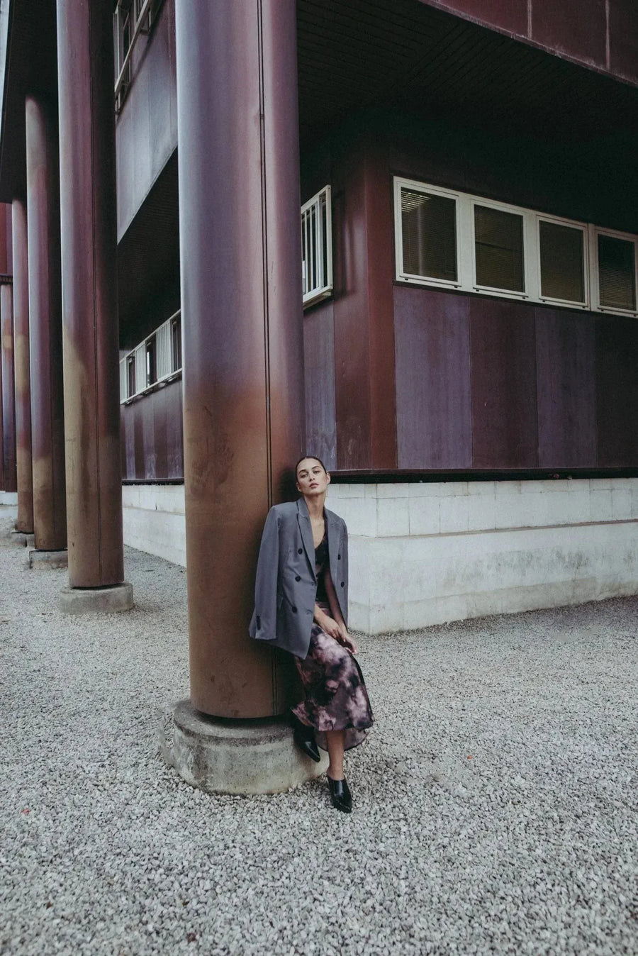 Modèle relaxant dans une robe tie dye longue satinée noir et rose au milieu d'un cadre moderne.