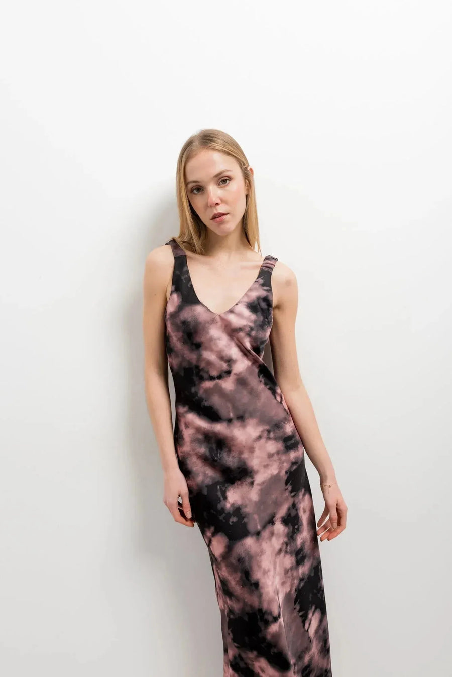 Modèle posant avec une robe tie dye longue satinée noir et rose, affichant un look moderne.