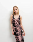 Modèle posant avec une robe tie dye longue satinée noir et rose, affichant un look moderne.