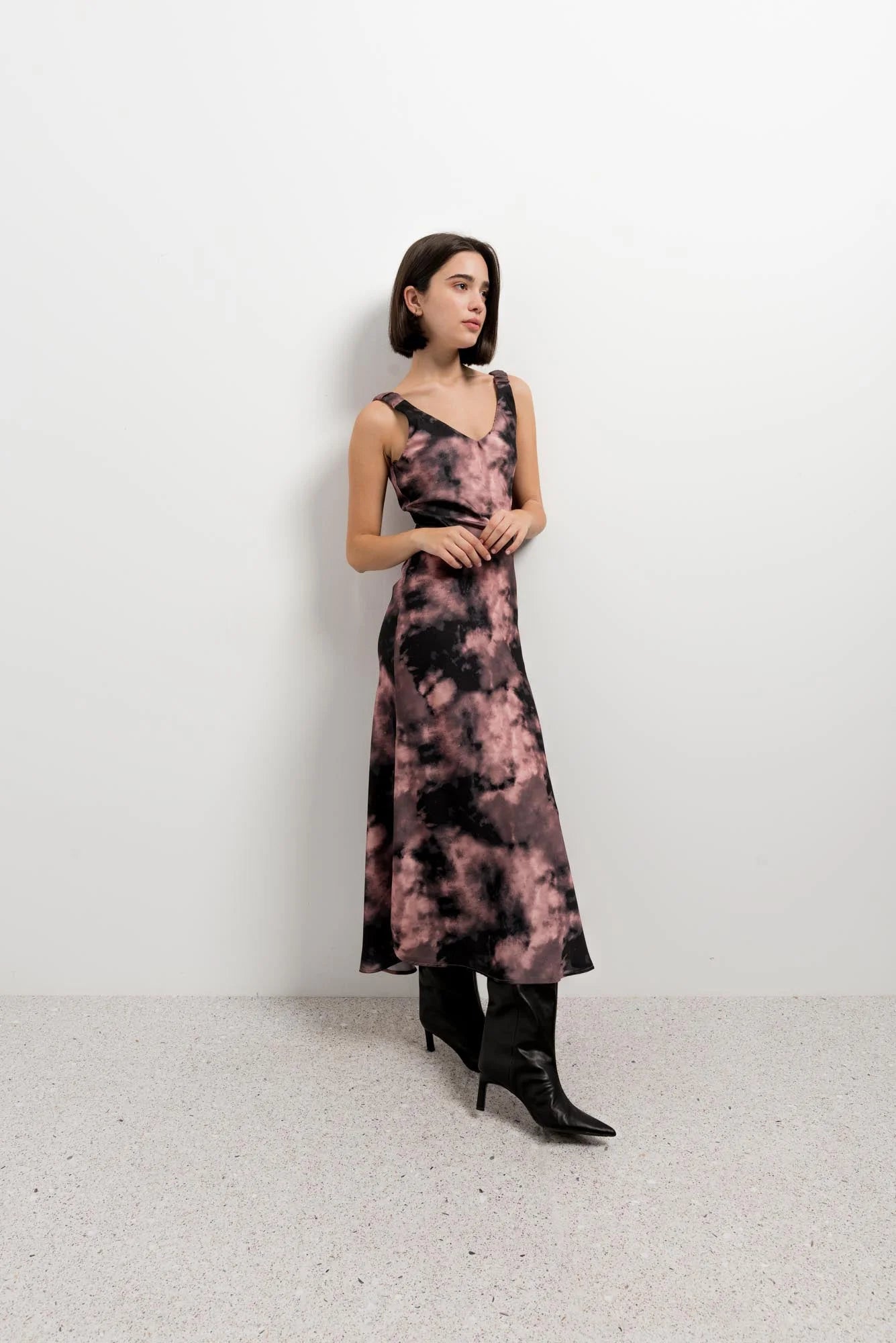Femme portant une robe longue satinée tie-dye noire et rose avec col V et bretelles larges
