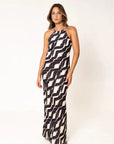 Robe Longue Col Halter Imprimée Graphique Noir et Beige – Élégance Estivale. Mannequin portant la robe longue col halter devant un fond neutre, la silhouette mise en valeur.