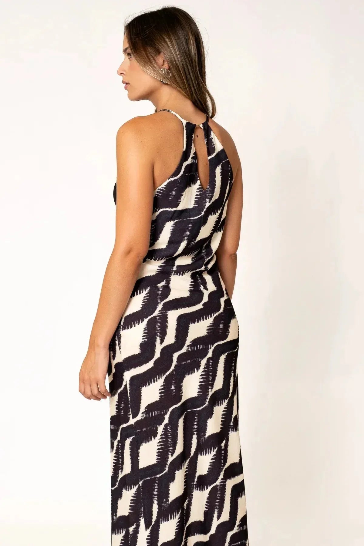 Robe Longue Col Halter Imprimée Graphique Noir et Beige – Élégance Estivale. Vue de dos d'une femme dans une robe longue col halter, mettant en avant le design élégant.