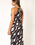Robe Longue Col Halter Imprimée Graphique Noir et Beige – Élégance Estivale. Vue de dos d'une femme dans une robe longue col halter, mettant en avant le design élégant.