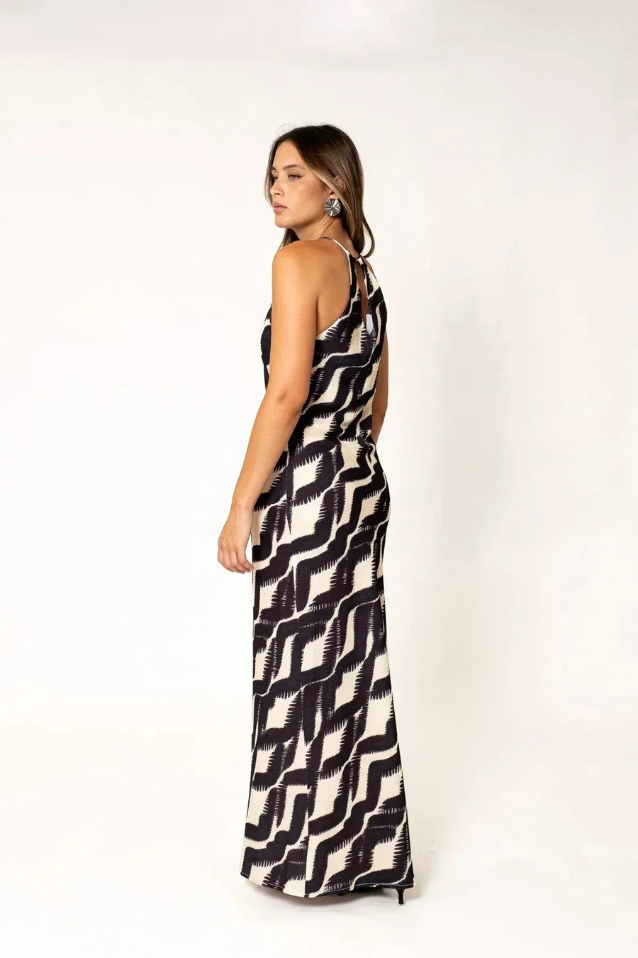 Robe Longue Col Halter Imprimée Graphique Noir et Beige – Élégance Estivale. Femme montrant le dos de la robe longue col halter, mettant en valeur son élégance sophistiquée.