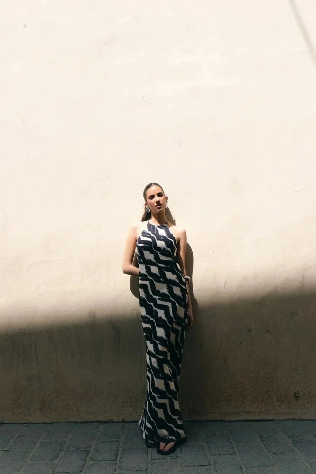Robe Longue Col Halter Imprimée Graphique Noir et Beige – Élégance Estivale. Femme posant avec un style chic dans une robe longue col halter au design graphique.