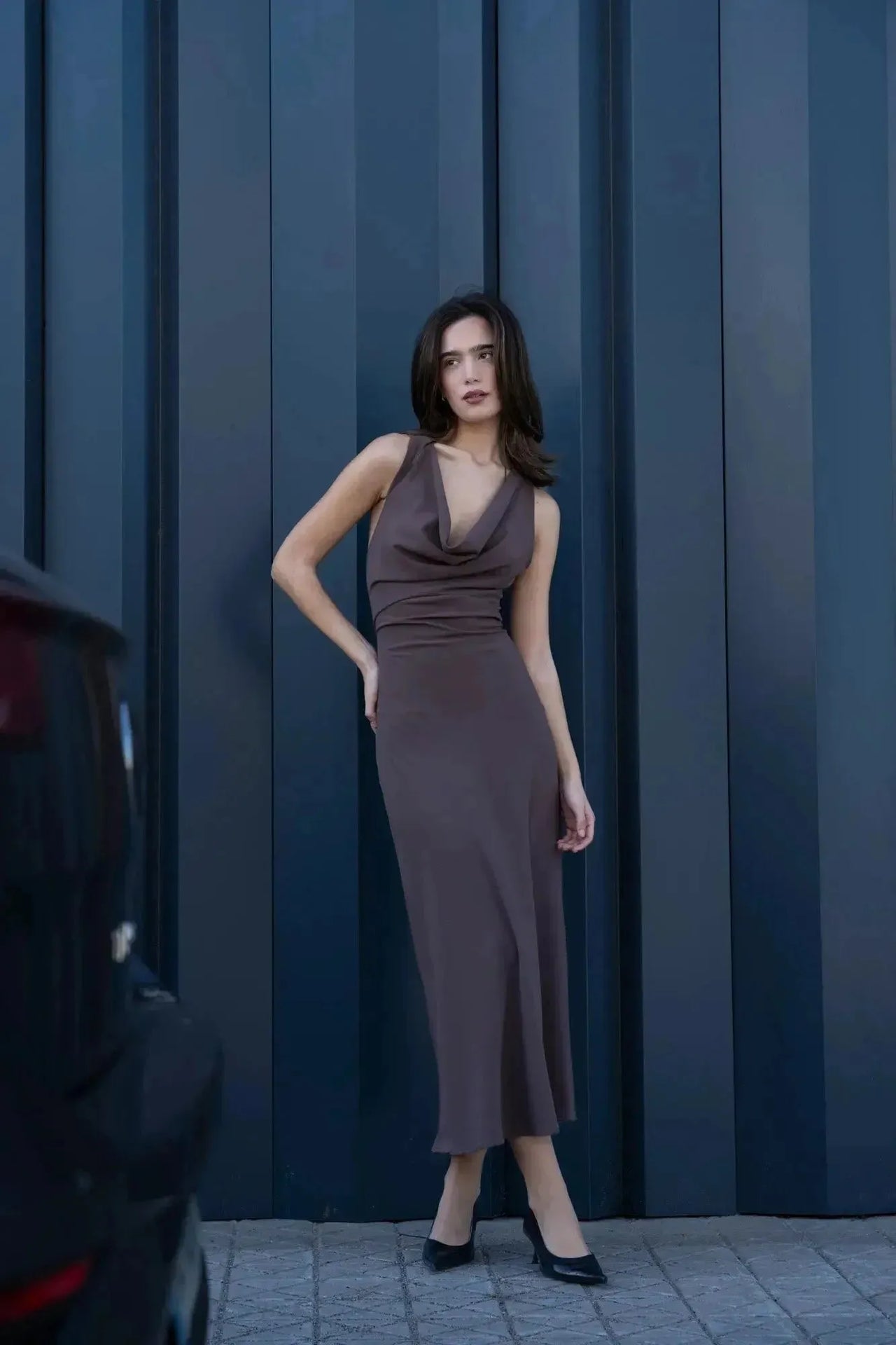 Femme posant dans une robe longue mariage civil détail doré, mettant en valeur la robe longue dos nu avec une allure chic en extérieur.