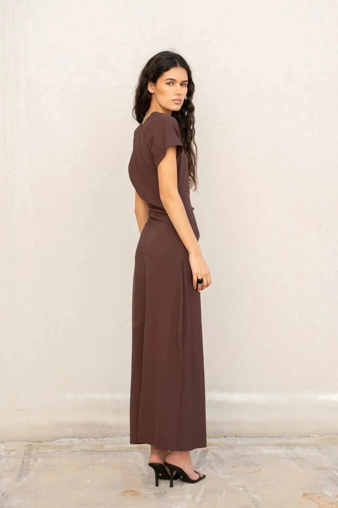 Robe longue marron ajustée femme avec détails drapés, vue de profil d'un modèle.