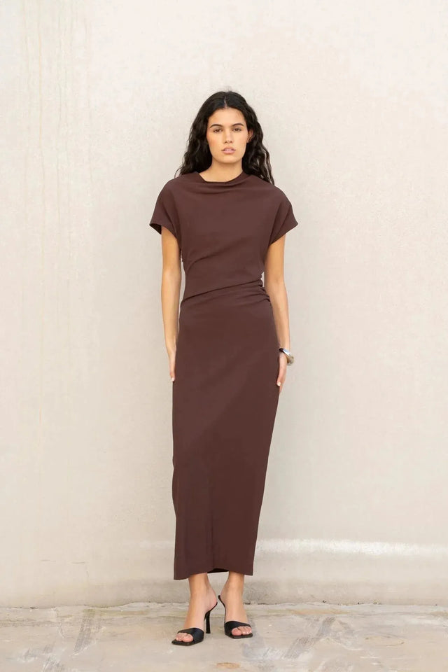 Robe longue marron ajustée femme avec détails drapés, modèle posant de face avec des pieds visibles.