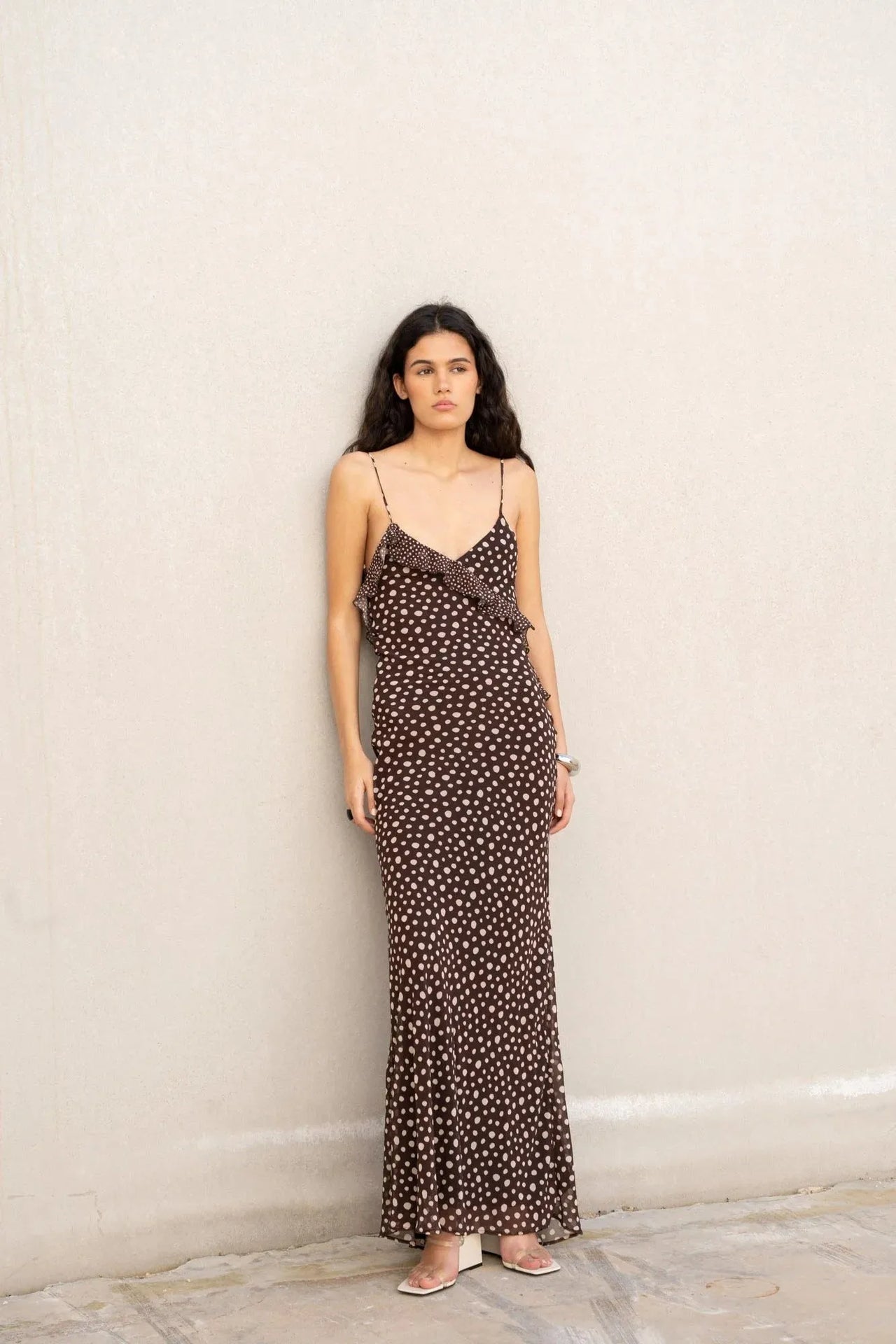 Robe longue marron à pois et volants, modèle féminin en position debout, affichant le design fluide de la robe à pois marron.