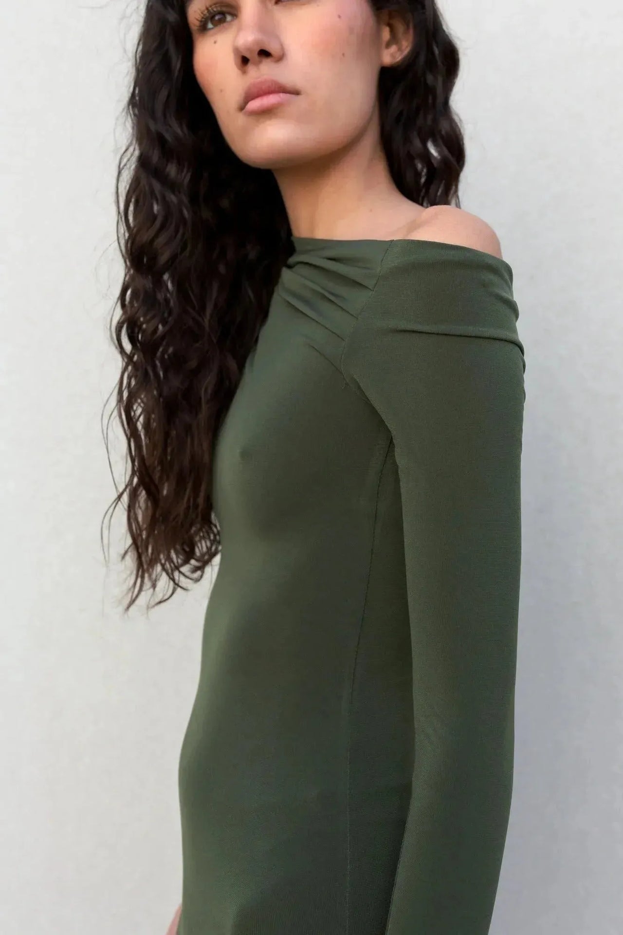 Portrait d'une femme en robe moulante kaki femme à épaule dénudée, mettant en avant le style sophistiqué de la robe moulante kaki.