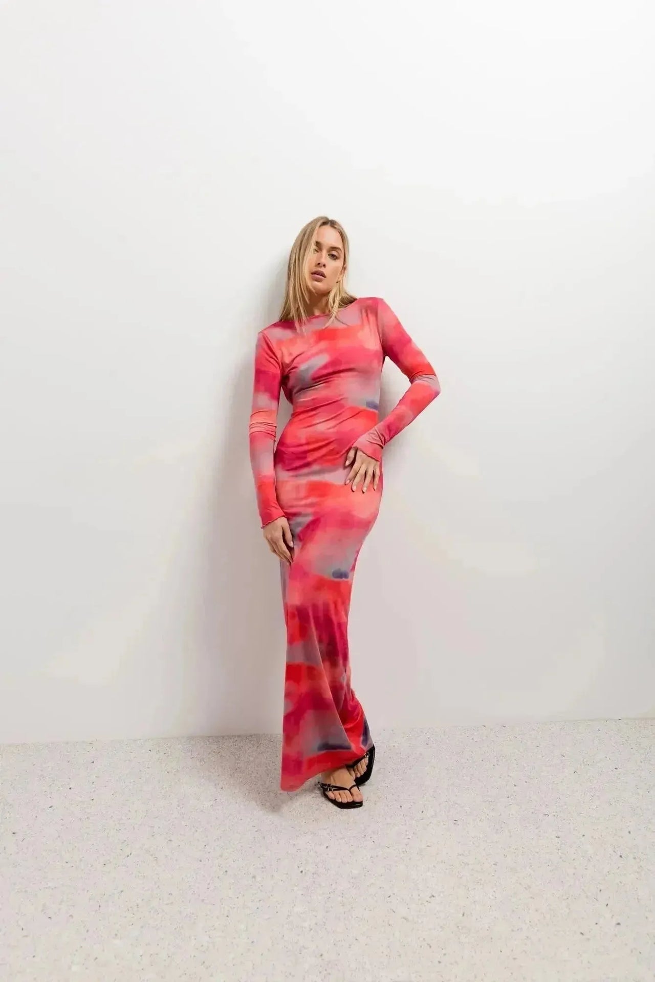 Femme affichant un look élégant dans une robe moulante pour femme tie-dye à manches longues, prenante une pose décontractée.