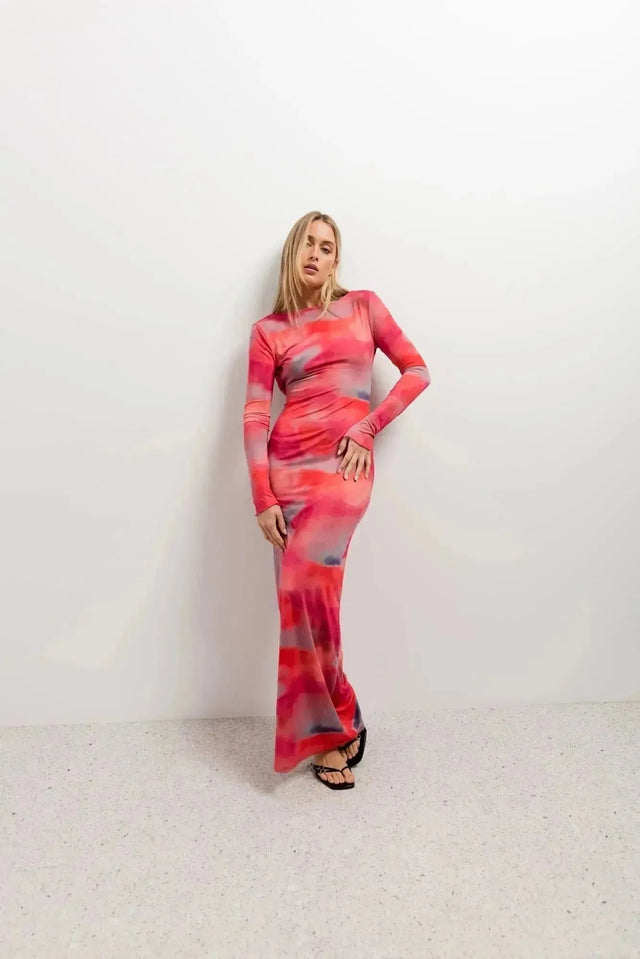 Femme affichant un look élégant dans une robe moulante pour femme tie-dye à manches longues, prenante une pose décontractée.