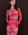 Modèle portant une robe moulante pour femme tie-dye à manches longues, design élégant, posant contre un fond en bois.