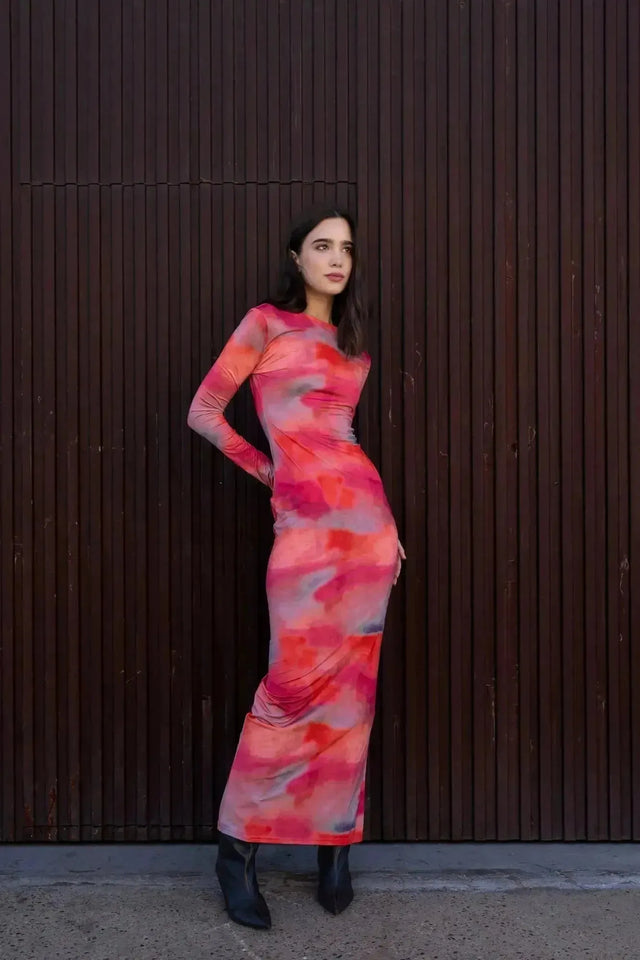 Femme en robe moulante pour femme tie-dye à manches longues, vue de profil, mettant en valeur le tissu coloré et la coupe ajustée.