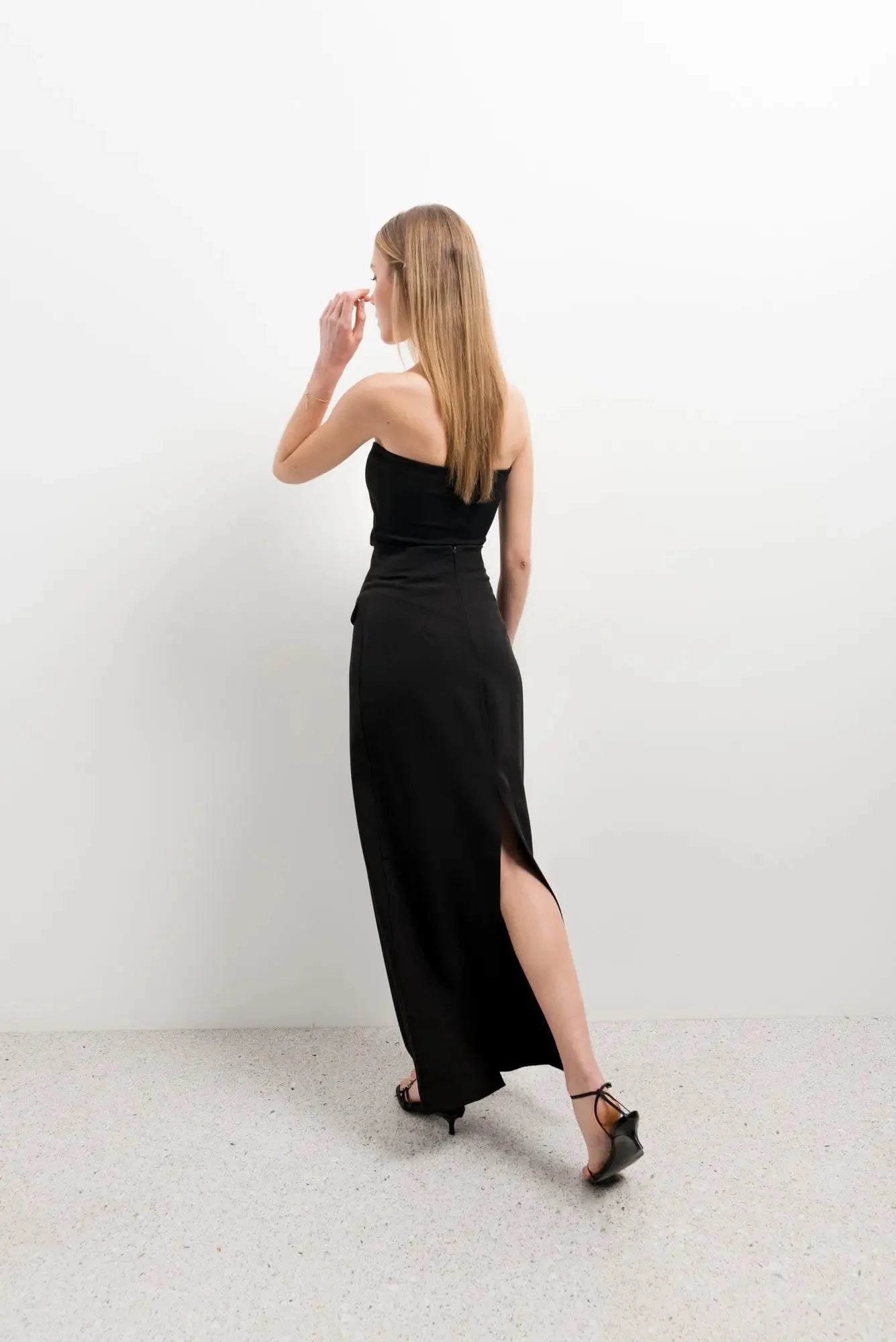 Femme portant une jupe midi avec fente latérale et top noir strapless