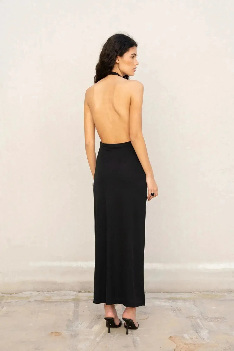 Vue arrière de la robe longue noire dos nu, révélant son design élégant. Un choix idéal pour une robe longue pour mariage invité chic.