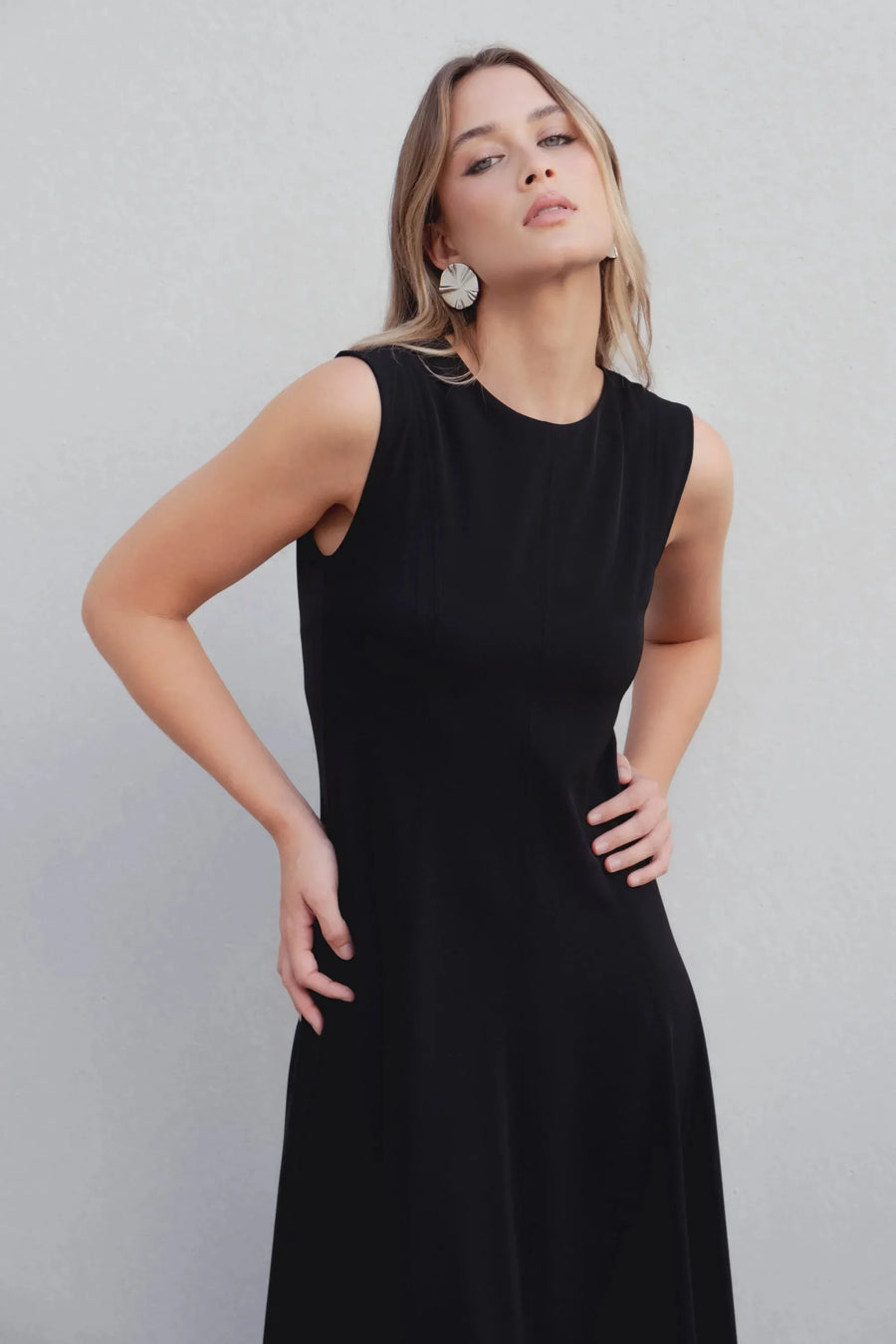 Robe Longue Noire Élégante Sans Manches - Coupe Midi, Ourlet Festonné, Col Rond, portée par un modèle féminin, montrant un look élégant et simple.