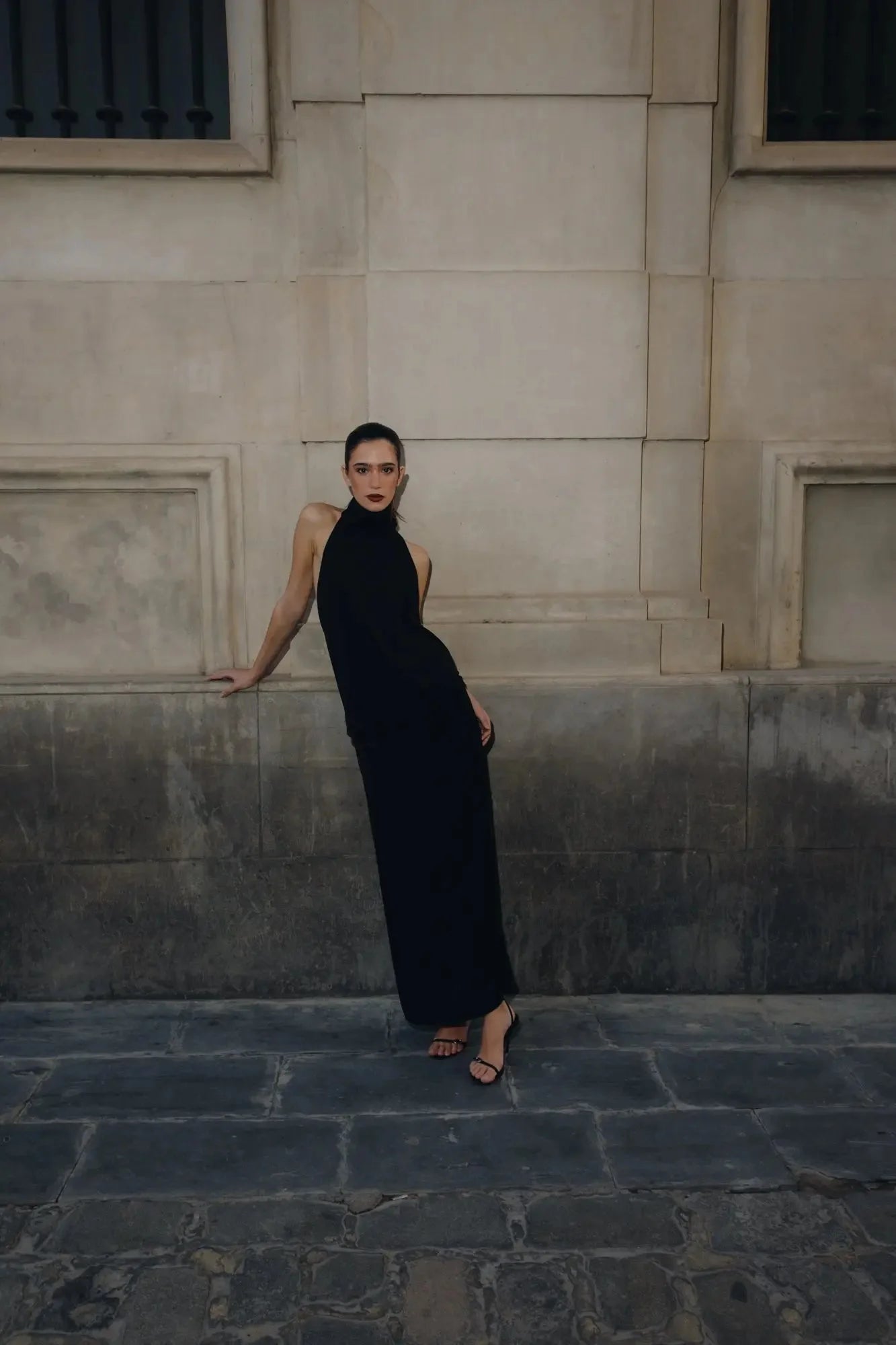 Femme en robe longue noire pour mariage civil et soirée chic avec hauts talons ouvertes