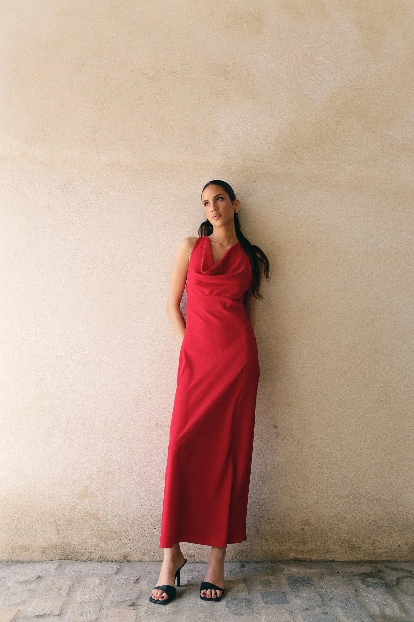 Femme portant une robe longue rouge dos nu col bénitier avec mules noires ouvertes