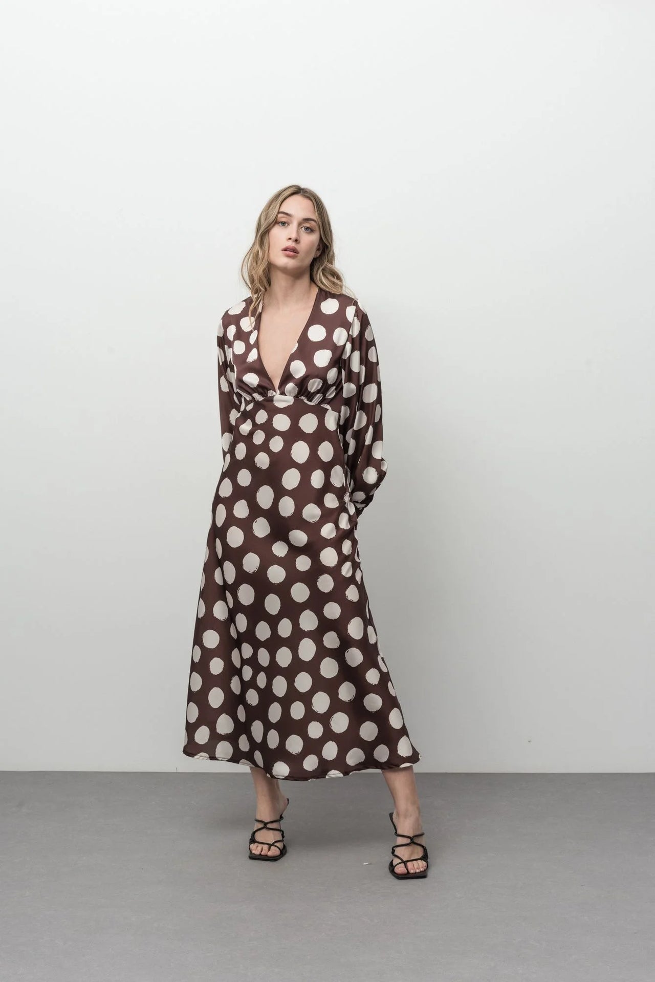 Robe marron à pois blancs midi chic satinée avec une allure tendance, idéale pour des événements élégants.