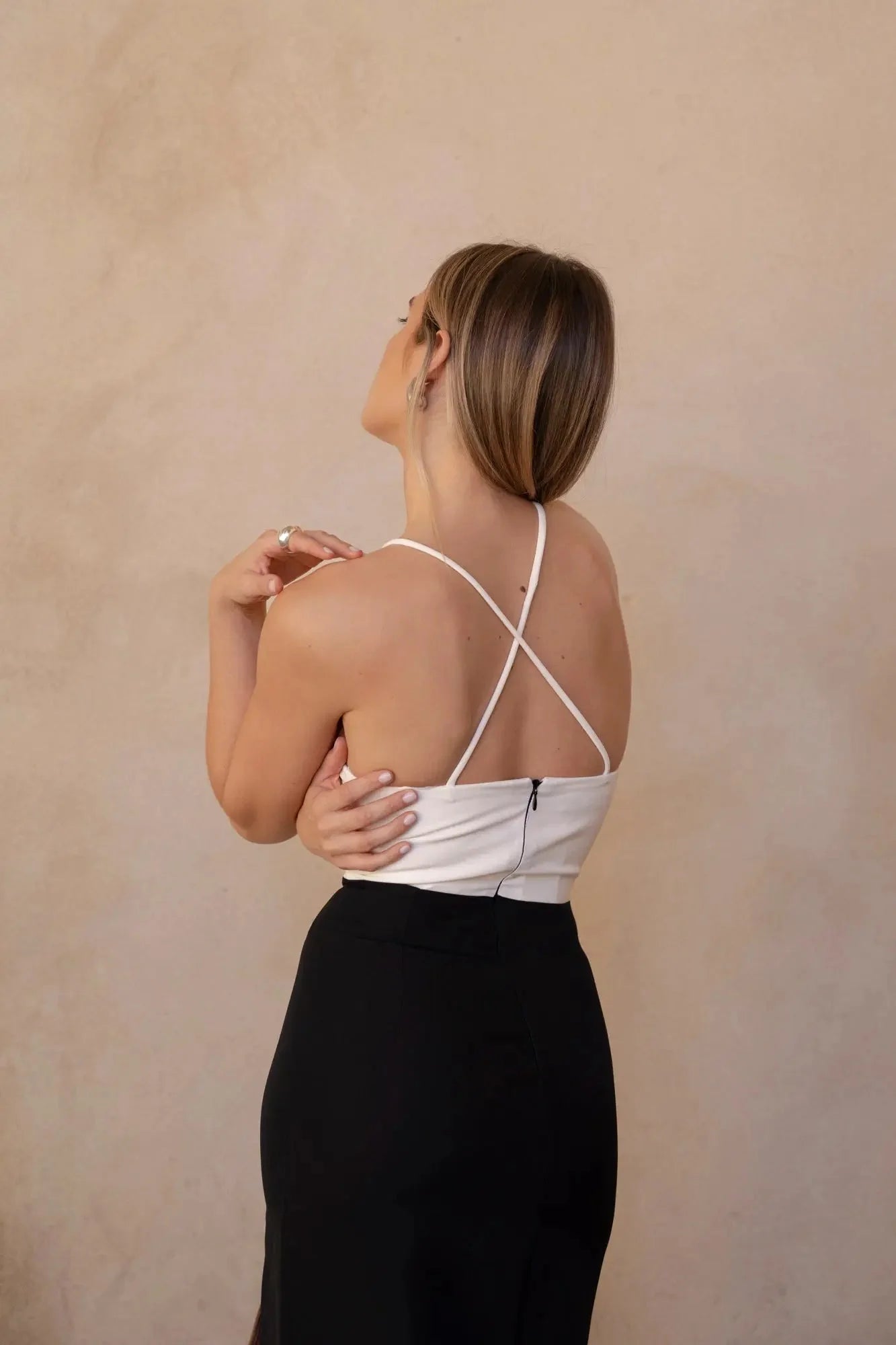 Vue arrière d'une robe marron femme midi bicolore à bretelles, montrant le style croisé des bretelles sur un fond neutre.