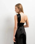 Vue arrière d'une modèle dans une robe de soirée femme midi asymétrique noire, présentant une encolure chic et un tissu fluide.