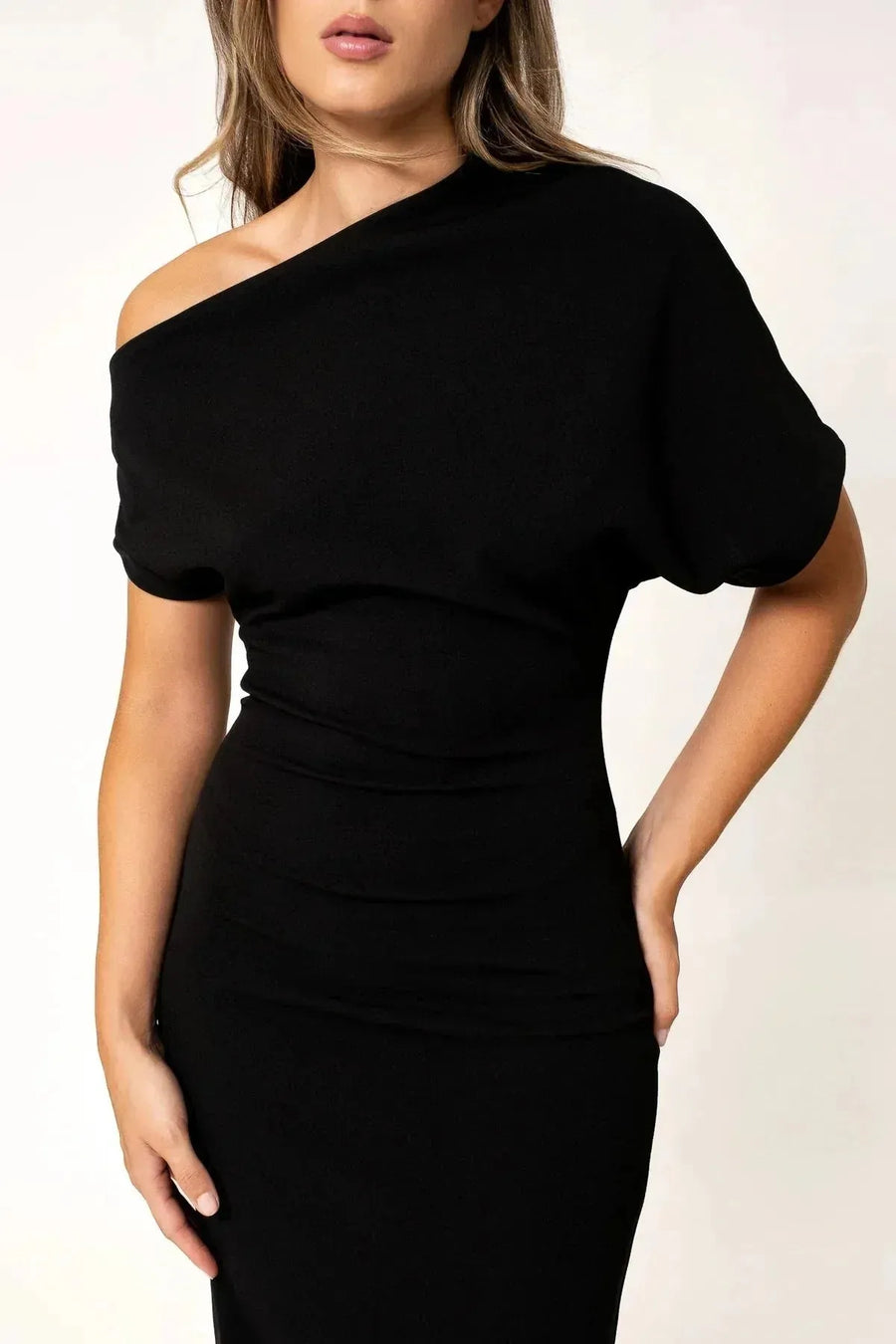Robe asymétrique mi longue noire femme, élégance versatile pour soirées tendance 2024. Détail rapproché du modèle féminin, illustrant le tissu fluide et la coupe moderne.