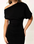 Robe asymétrique mi longue noire femme, élégance versatile pour soirées tendance 2024. Détail rapproché du modèle féminin, illustrant le tissu fluide et la coupe moderne.