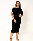 Robe asymétrique mi longue noire femme, élégance versatile pour soirées tendance 2024. Modèle féminin posant avec assurance, mettant en valeur la robe en noir élégant.