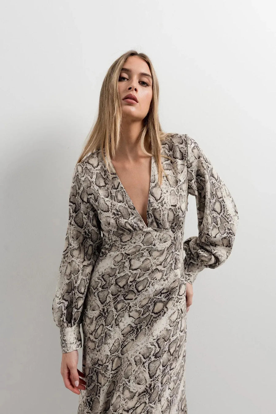 Femme portant une robe midi imprimé python à col cache-cœur, mettant en avant le motif reptile tendance, parfaite pour un look sauvage et sophistiqué. Idéale pour les amateurs de mode en quête d'une robe animal.