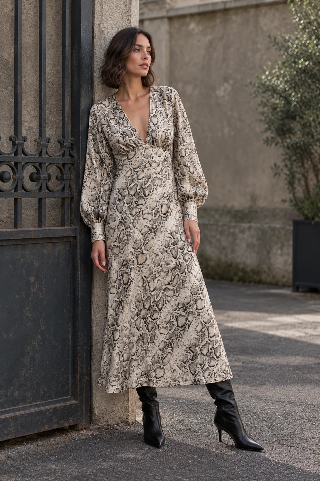 Modèle avec une robe midi imprimé python à col cache-cœur, posant avec style. La coupe fluide et les manches bouffantes soulignent l’élégance de cette robe animal.