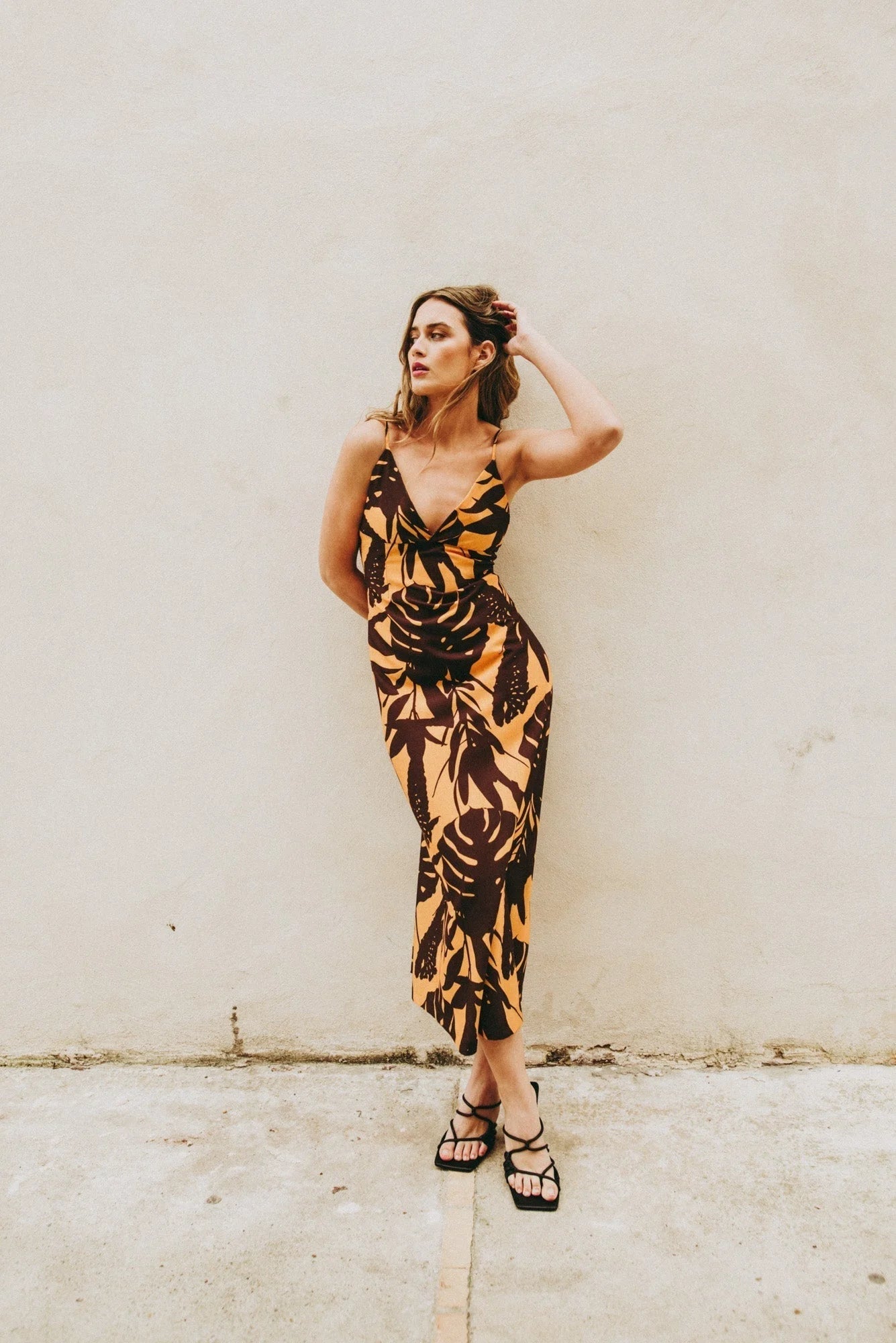 Femme portant une robe midi imprimée fleurie en tissu léger et sandales noires élégantes