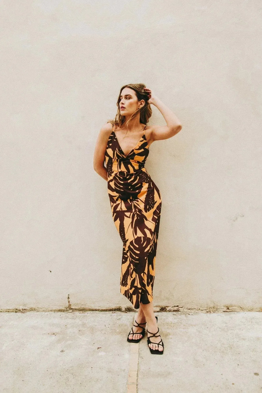 Femme posant dans une robe imprimé tropical midi floral marron et jaune au design élégant et confortable.