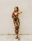 Femme posant dans une robe imprimé tropical midi floral marron et jaune au design élégant et confortable.