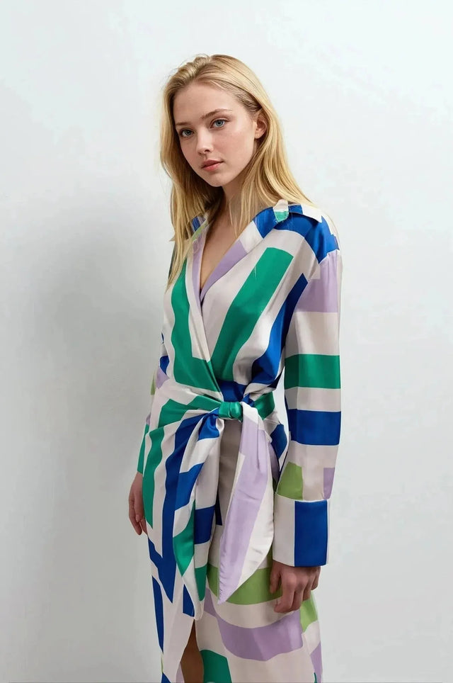 Modèle portant une robe midi imprimée portefeuille géométrique avec des motifs colorés. Élégance et confort pour toutes occasions.