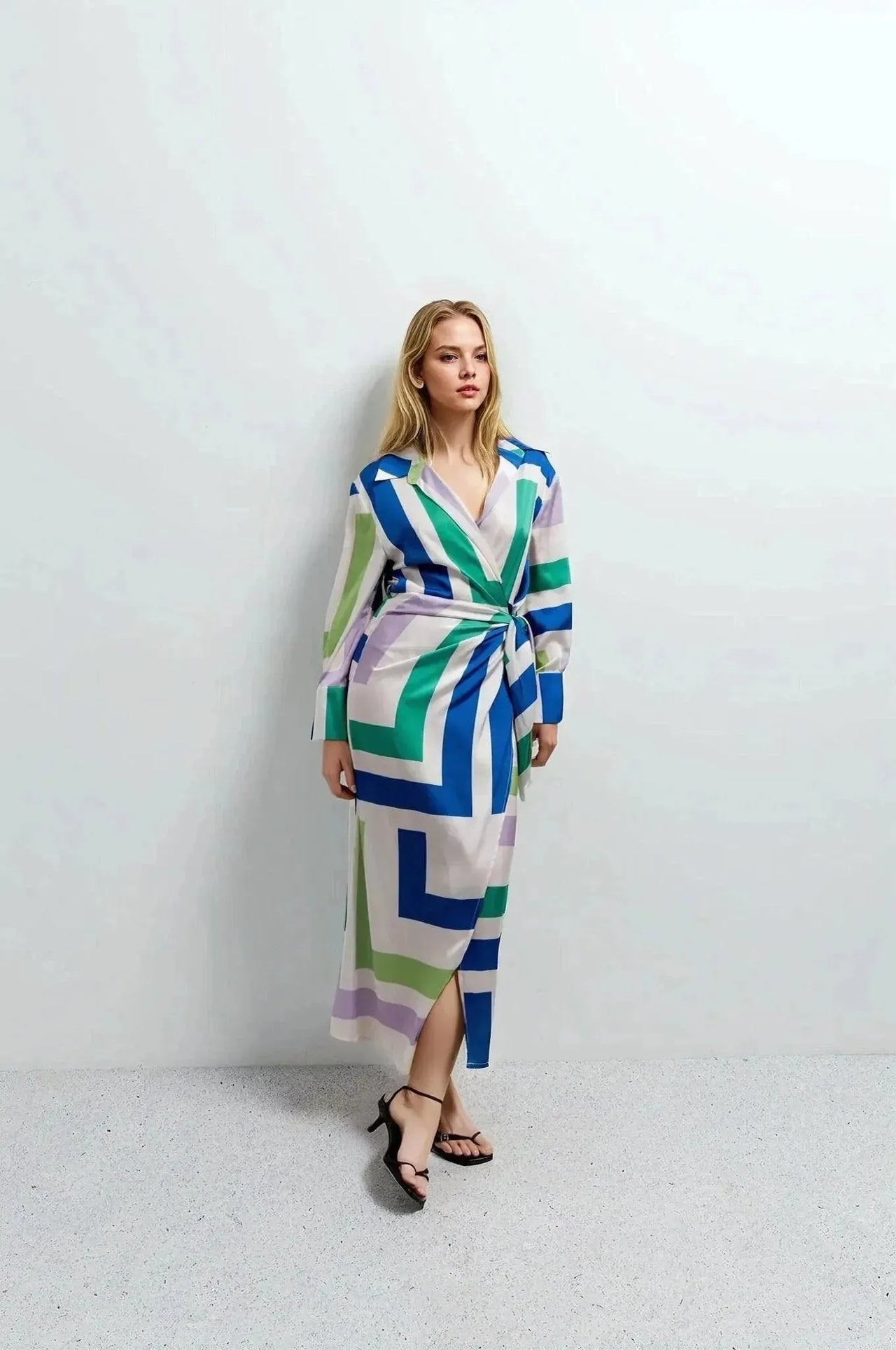 Vue de face d'une femme en robe midi imprimée portefeuille géométrique. Style moderne, parfaite pour des événements décontractés ou formels.