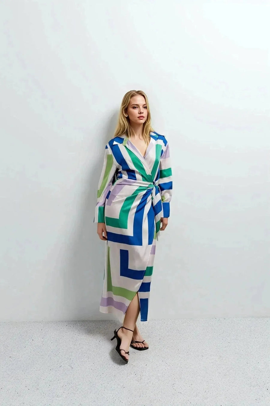 Vue de face d'une femme en robe midi imprimée portefeuille géométrique. Style moderne, parfaite pour des événements décontractés ou formels.