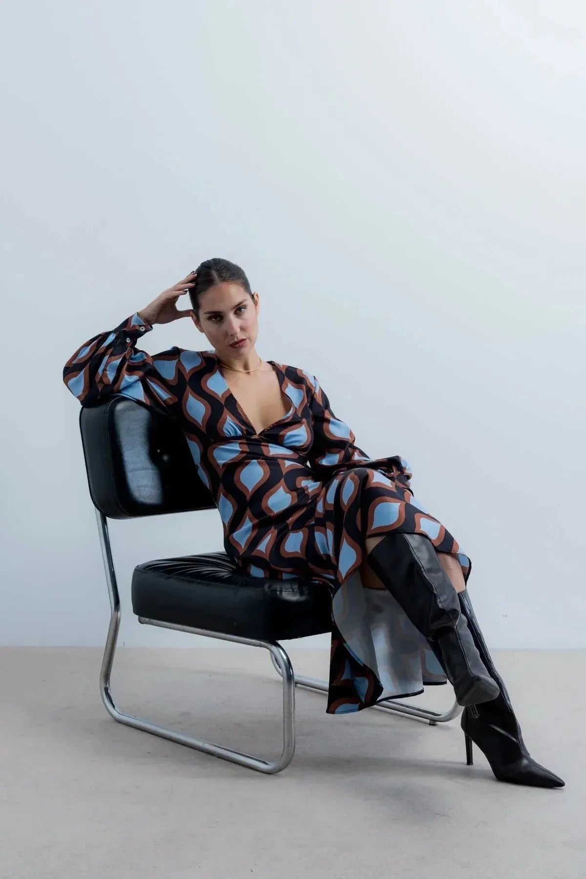 Femme posant dans une robe motif géométrique midi à décolleté profond et manches bouffantes, combinant élégance et audace.