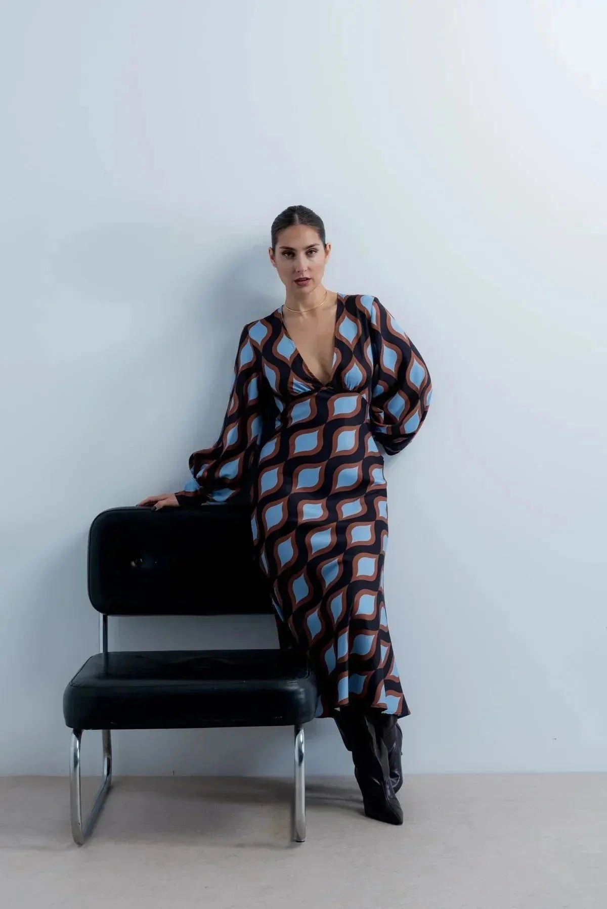 Femme stylée dans une robe motif géométrique midi avec un décolleté V profond, affichant une allure chic et contemporaine.