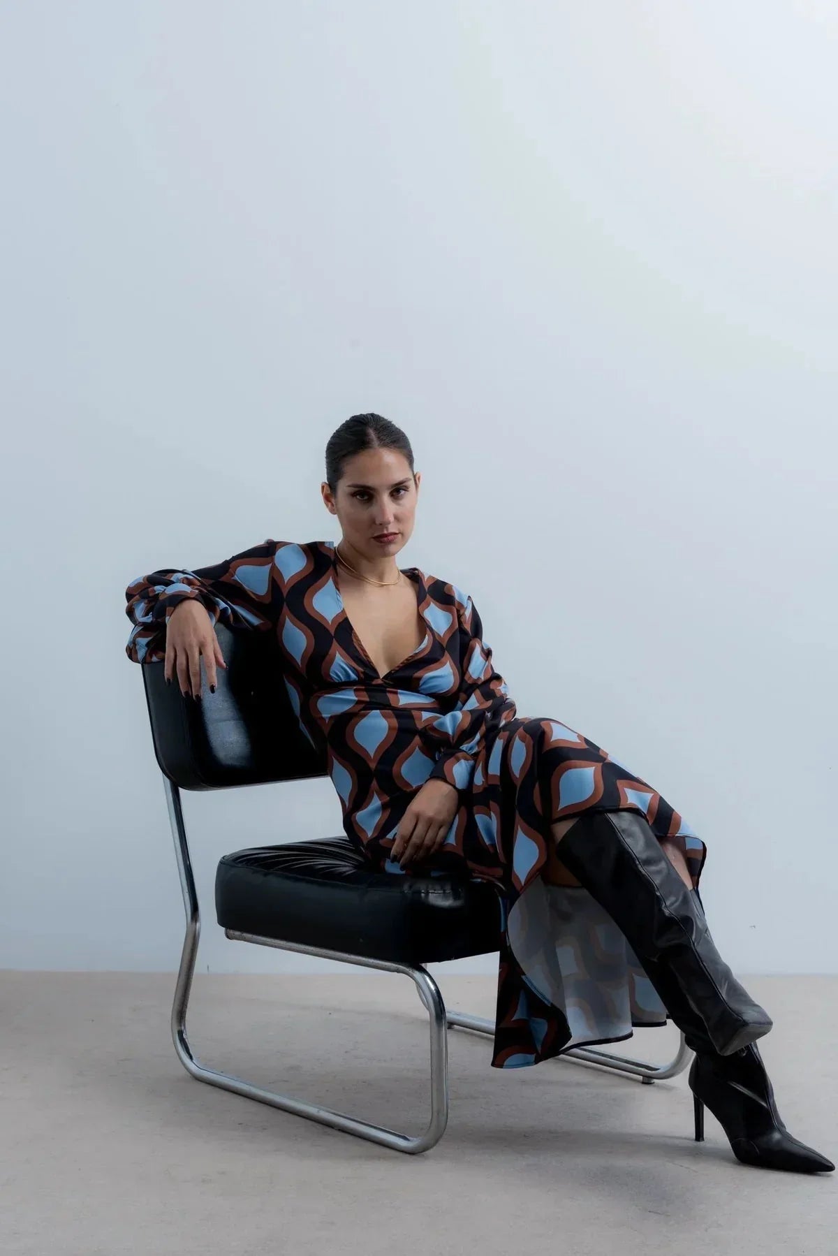 Femme portant une robe midi imprimée vagues géométriques et bottes noires hautes