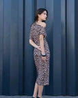 Femme en robe midi léopard à motif animalier de profil, affichant un look tendance parfait pour une soirée. Robe léopard longue et élégante.