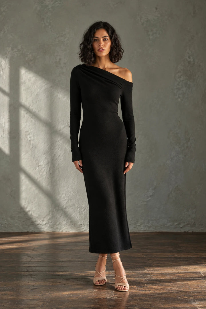 Femme portant une robe midi noire à coupe asymétrique, mettant en valeur la robe maille avec des détails élégants et une silhouette flatteuse.