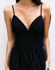 Zoom sur la partie supérieure d'une robe midi noire à fines bretelles, illustrant le détail du décolleté en V et le smocké élégant. Cette robe noire longue dos nu est un must-have.