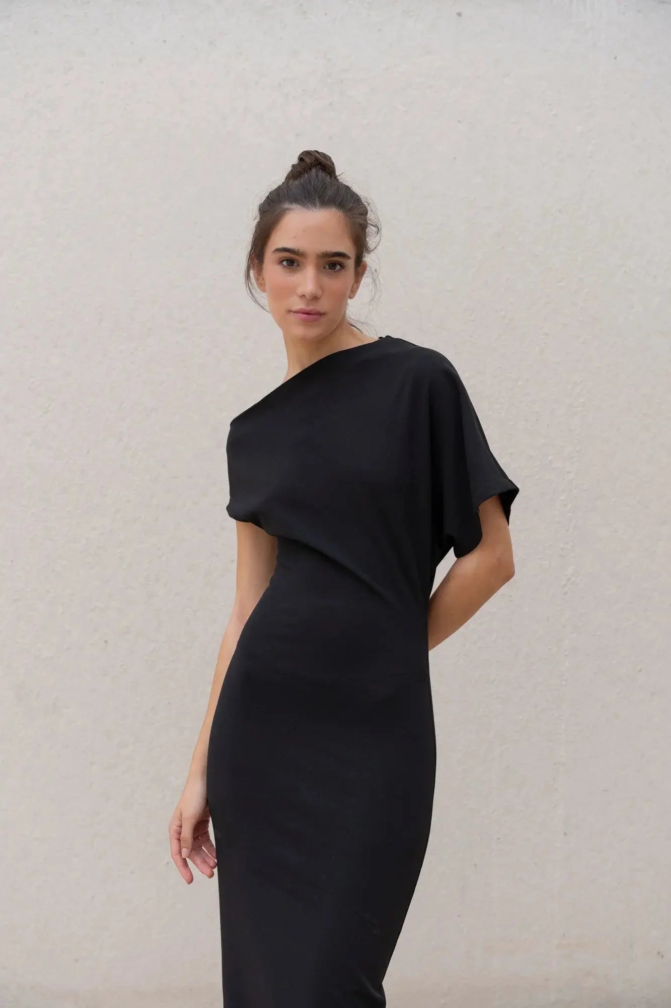 Femme en robe noire asymétrique élégante à épaule dénudée, coupe midi