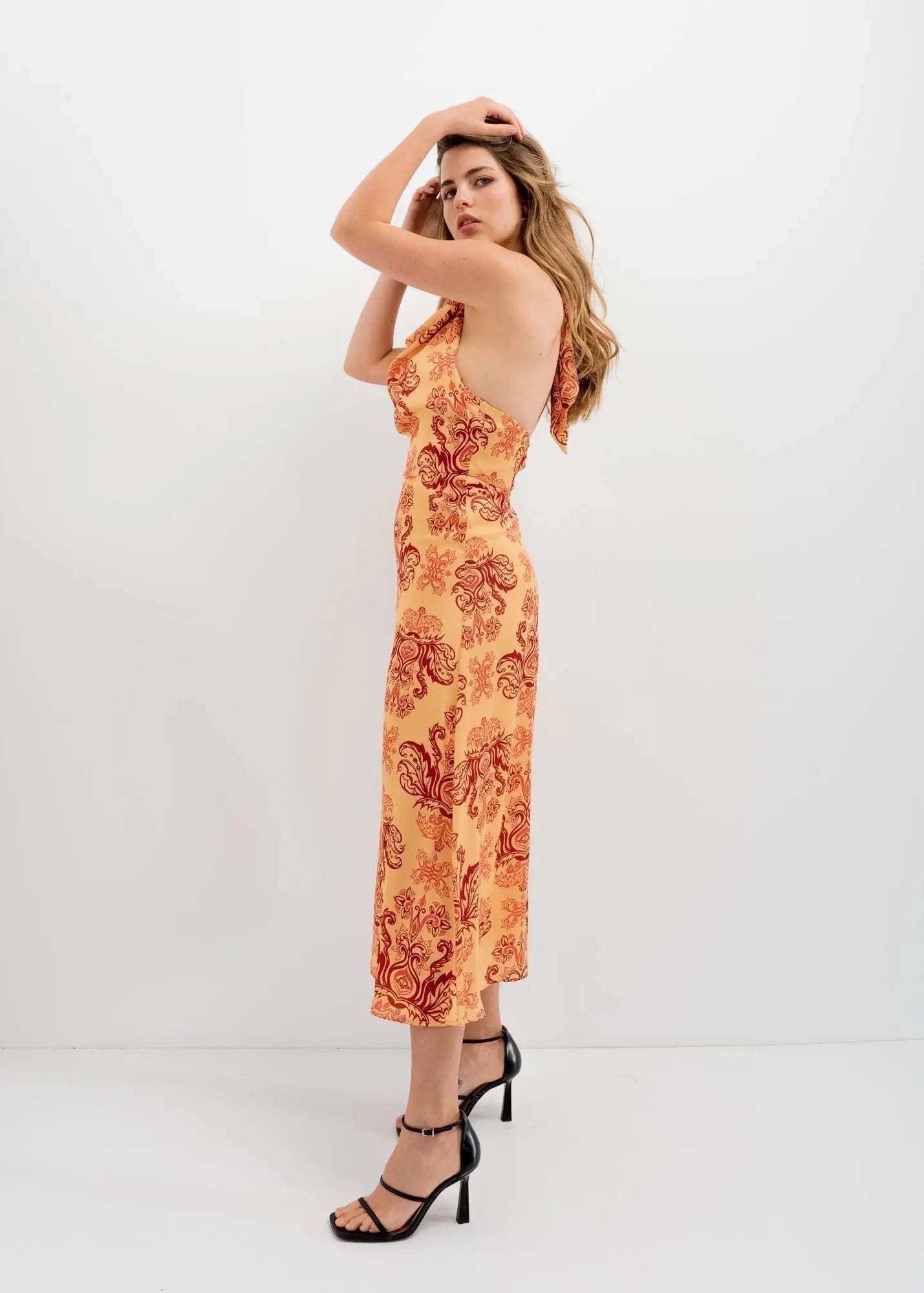 Robe longue orange imprimée chic avec dos nu et sandales à talons noirs